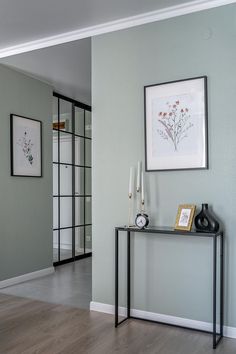 a living room with a table and some pictures on the wall next to each other