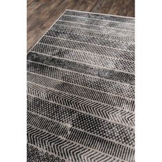 a black and white rug with an abstract design on the bottom, in front of a wooden