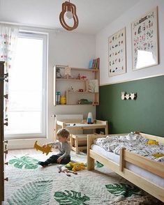 a little boy sitting on the floor playing with toys in a bedroom next to a window