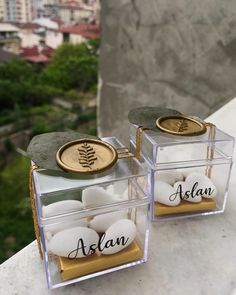 two clear acrylic boxes with rocks in them on top of a stone wall