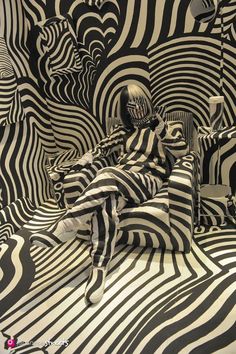 black and white photograph of a woman sitting in a room with zebra stripes on the walls