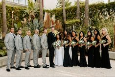 a group of people standing next to each other in front of some trees and bushes