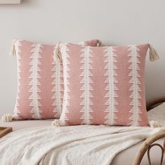 two pink and white pillows sitting on top of a bed