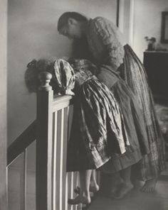 an old photo of a woman leaning on a railing with her doll in the corner