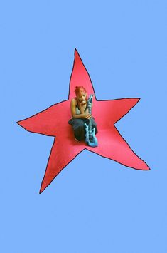 a man sitting on top of a red star shaped object in the sky with a cell phone