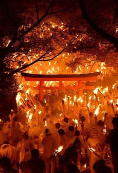 a group of people standing in front of a red tori tori shrine with fire coming from it