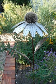 a large metal flower sitting in the middle of a garden