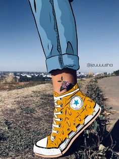 a person's feet with tattoos on them and yellow converse shoes in the grass