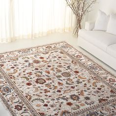 a living room with a white couch and large rug on the floor in front of a window