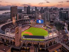 an aerial view of a baseball stadium in the city at sunset or dawn with lights on