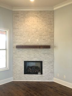 an empty living room with a fireplace in the middle and hard wood flooring on the other side