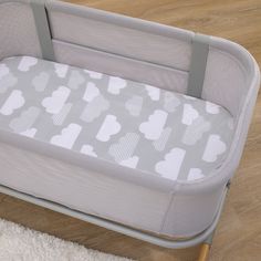 a baby crib that is sitting on the floor next to a rug and wooden floor