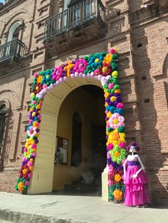 a woman standing in front of a building decorated with flowers and pom poms