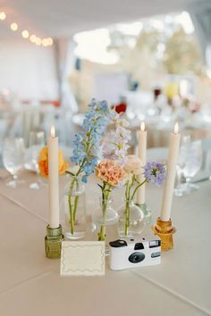 flowers and candles are arranged in vases on the table