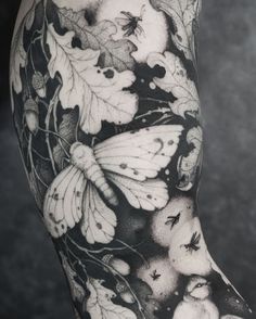 a black and white photo of a woman's leg with butterflies on it