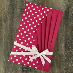 six red and white polka dot paper napkins tied together with ribbon on wood background