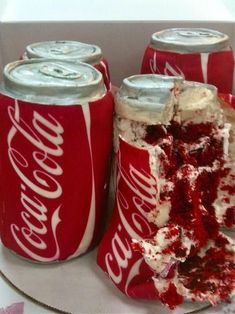 a cake in a box with coca - cola cans on it and one slice missing