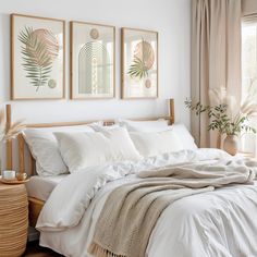 a bed with white linens and pillows in a bedroom next to two pictures on the wall