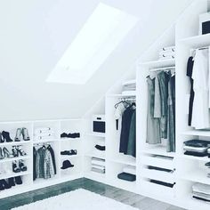 a white closet with lots of clothes hanging on the walls and shelves in front of it