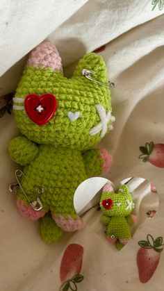 a green crocheted teddy bear with a red heart on it