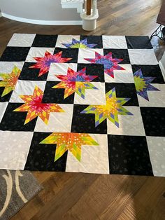 a black and white checkered table topper with colorful stars on it, sitting on a wooden floor