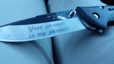 a pocket knife with a quote on it saying your pleasure is my pleasure, stuck in someone's lap