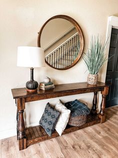 a wooden table topped with a mirror next to a vase filled with plants and pillows