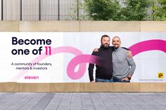 two men standing next to each other in front of a sign that says become one of it