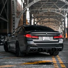 the back end of a black car parked under an overpass