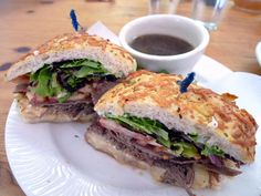 a sandwich cut in half sitting on top of a white plate next to a cup of coffee