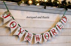 a banner that says joy to the world hanging from a mantle with garland on it