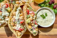 some tacos are sitting on a cutting board next to a bowl of ranch dressing