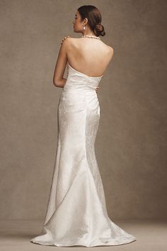 a woman in a white wedding dress looking off into the distance with her back to the camera