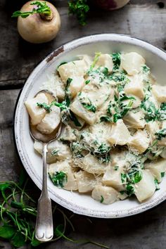 a white bowl filled with ravioli and spinach