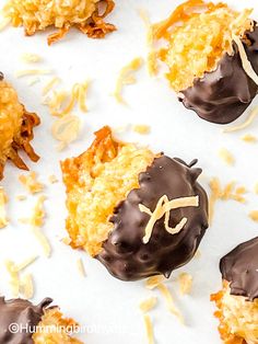 chocolate covered pastries with coconut flakes and sprinkles on a white surface