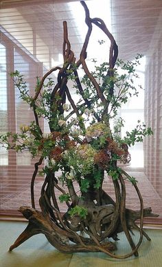 a vase filled with lots of flowers sitting on top of a wooden table next to a window