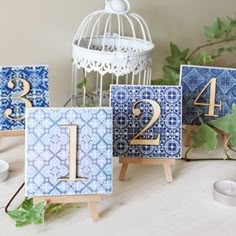 blue and white tiles with gold numbers are displayed on wooden easels next to a birdcage