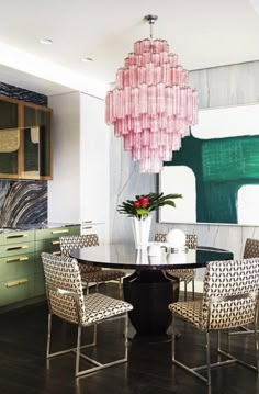 a dining room table with four chairs and a chandelier hanging from the ceiling