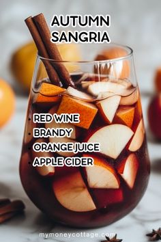 a glass filled with red wine, orange juice and apple cider next to cinnamon sticks