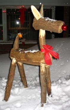 a wooden rocking horse made out of logs with a red ribbon on it's back