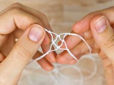 two hands are holding white string together