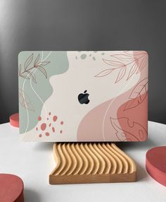 an apple laptop sitting on top of a white table next to pink and green circles