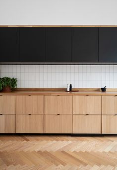 an empty kitchen with black cabinets and wood flooring on the walls, along with potted plants