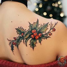 a woman's back tattoo with holly leaves and berries