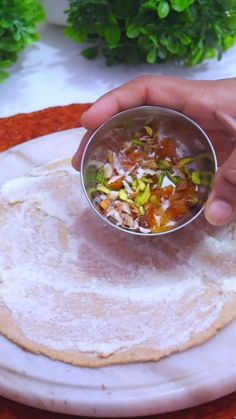 a person holding a small bowl with food in it on top of a white plate