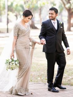 a bride and groom walking together in the park on their wedding day, holding hands