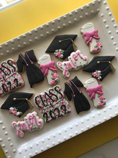 decorated cookies in the shape of graduation caps and gowns are on a white tray