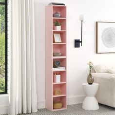 a pink bookcase in a living room next to a window