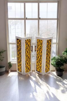 an open room divider in front of a window with potted plants next to it