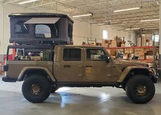 a jeep is parked in a warehouse with its roof tent on it's top